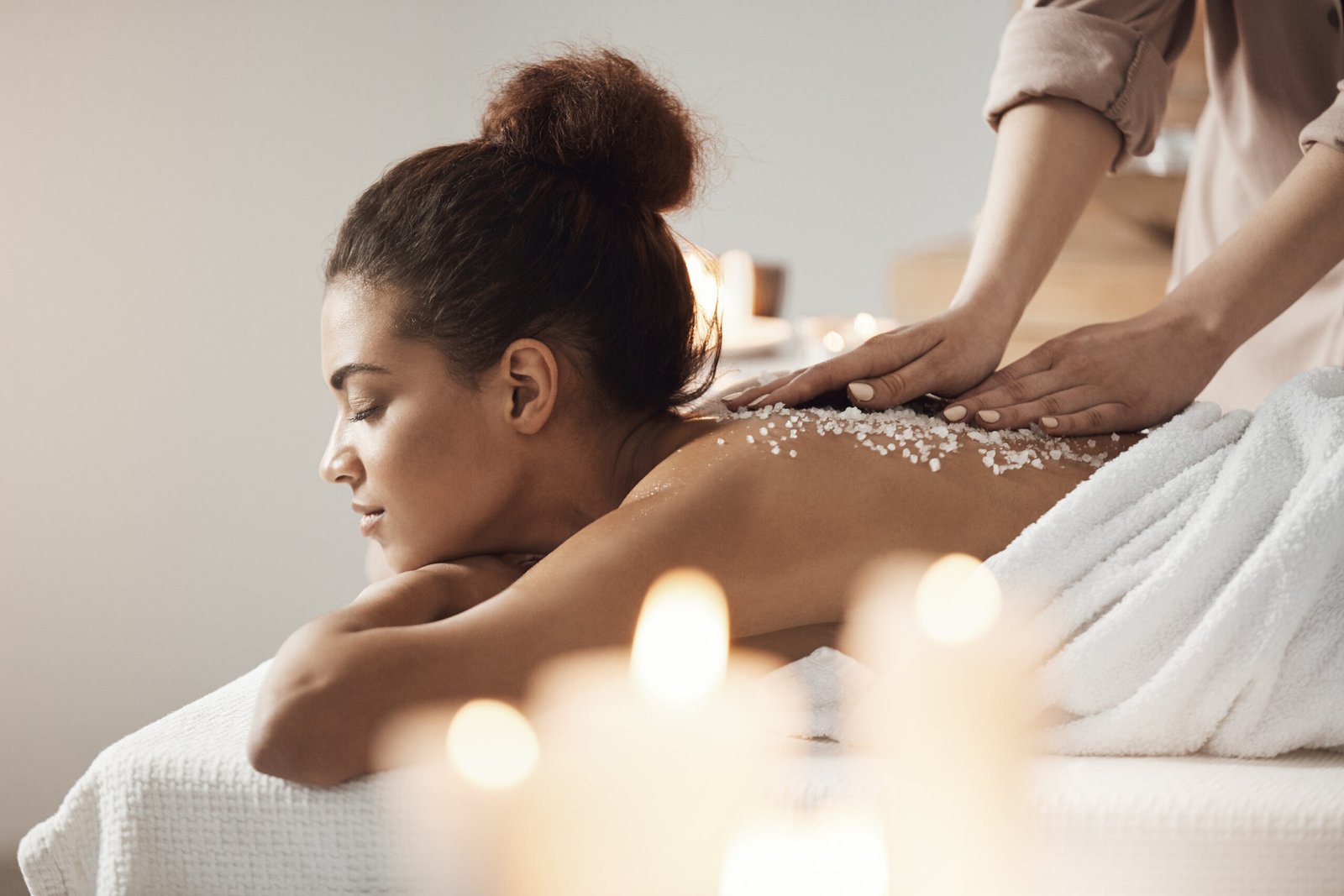 Beautiful african girl resting enjoying spa health massage with sea salt.