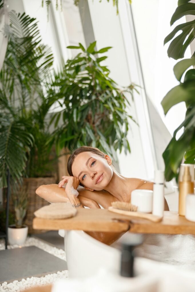 Peaceful young woman looking at camera while taking bubble bath at tropical spa resort